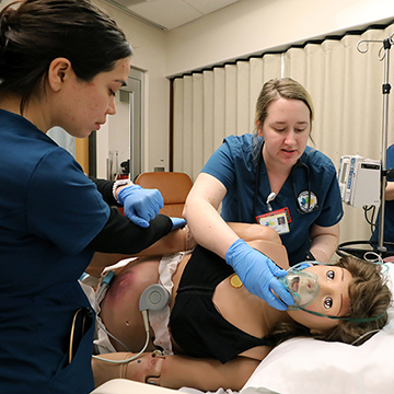 nursing students practice respiratory care on a simulation dummy