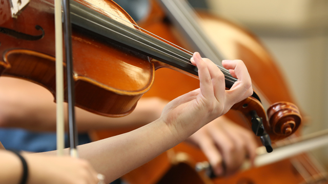 Close up photo of someone playing a violin. Only he hands are shown.