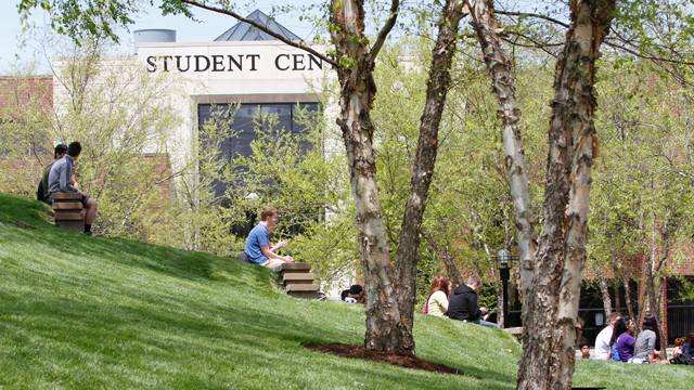 Students sitting on the hill in front of the Student Center in the summertime.