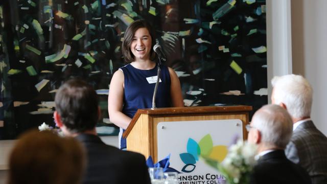 A smiling Sarah Patton at a podium presenting her research