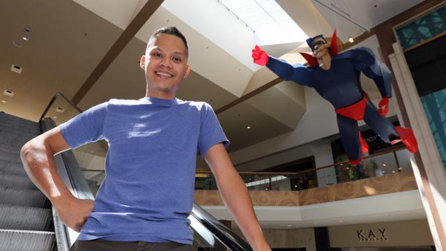 Juniper Tangpuz posing by a model of Superman in flight