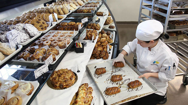 Student placing pastries in a display case