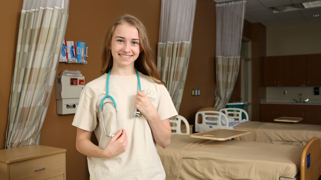 Brenna Nelson in a nursing classroom wearing a stethoscope