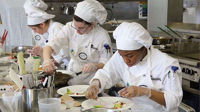 Culinary students prepare food in a kitchen