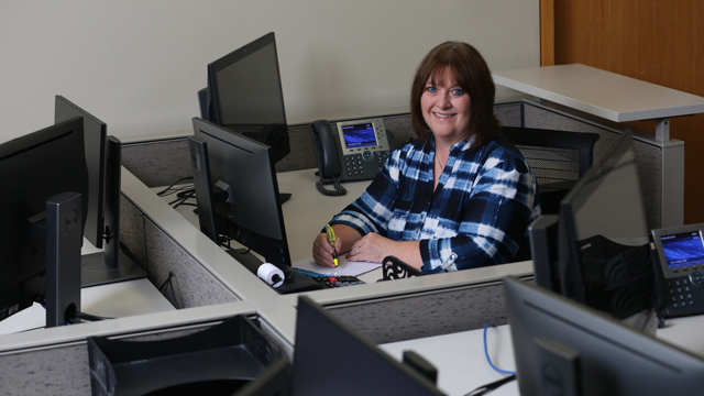 Debra Lind sitting at a desk in a Business Office Technology lab.