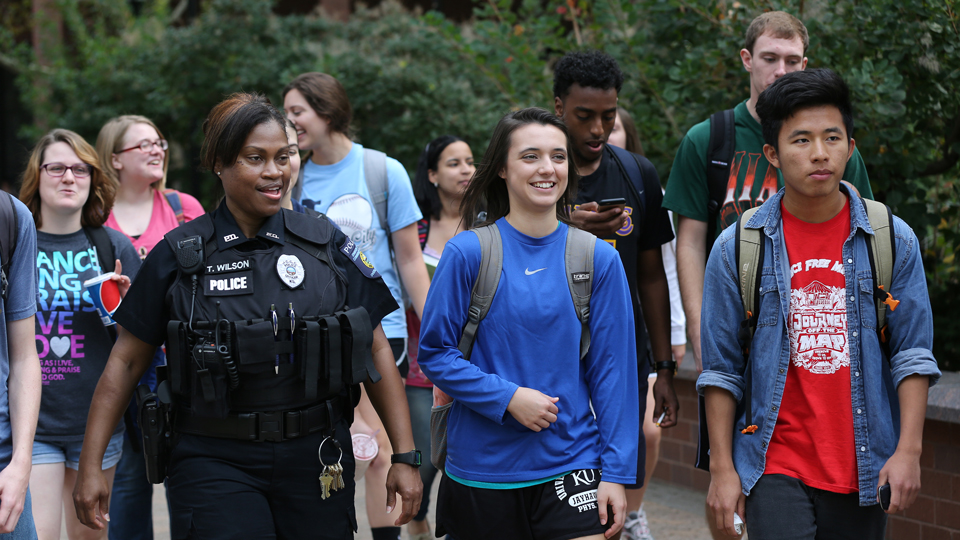JCCC police officer walking and talking with a group of students