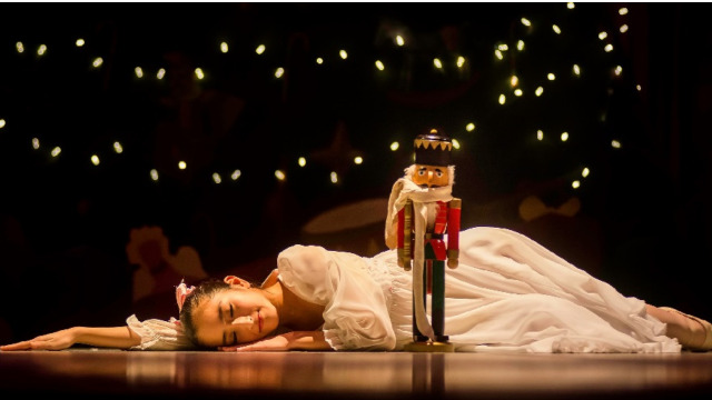 A young girl sleeps on the floor next to a Nutcracker doll.