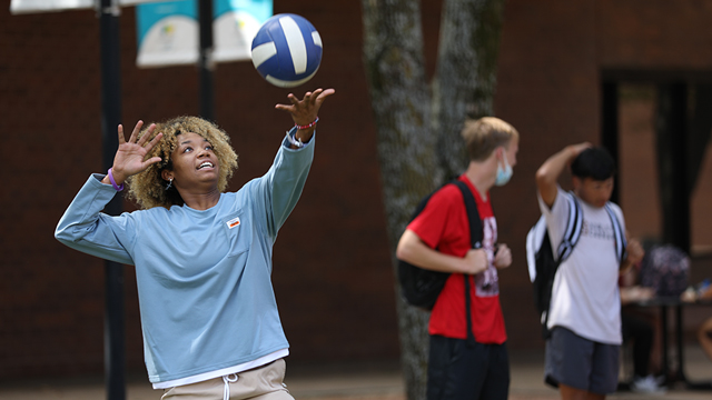 Three students playing recreational volleyball