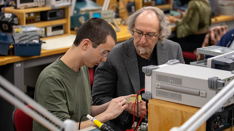 Student working with instructor on electronics technology project.
