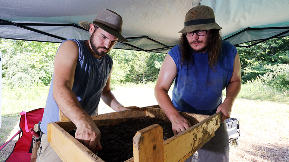 Two JCCC students sift dirt at an area dig site.