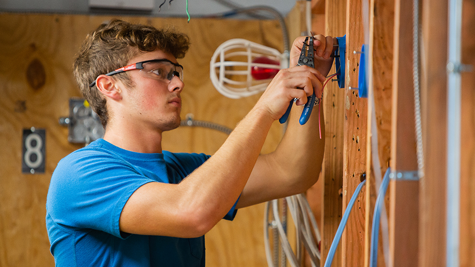 a man in safety glasses works on wiring