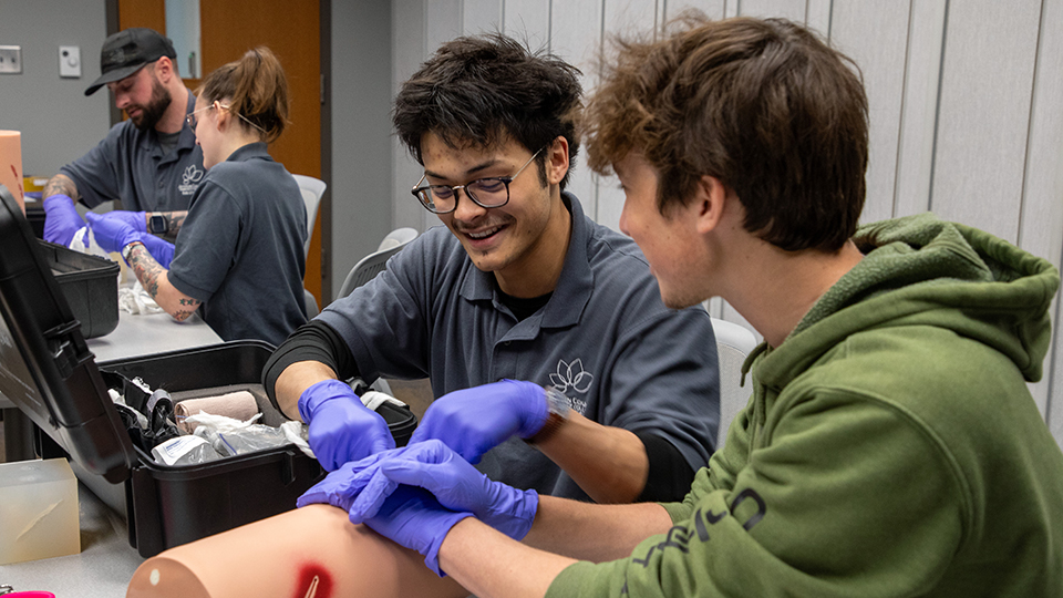 Students practice on a "stop the bleed" training device.