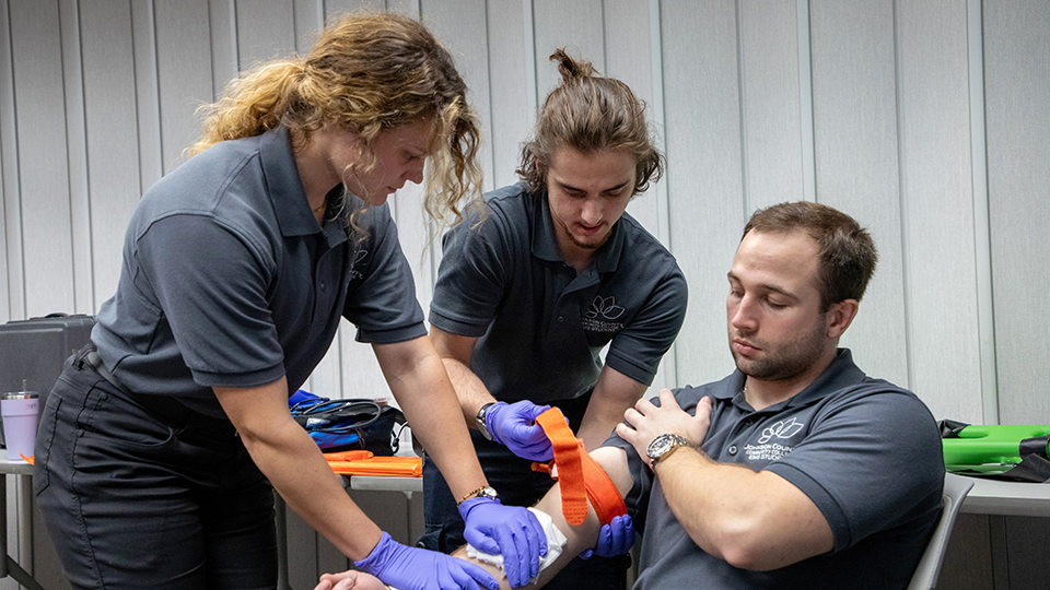 Three students practice a blood draw.