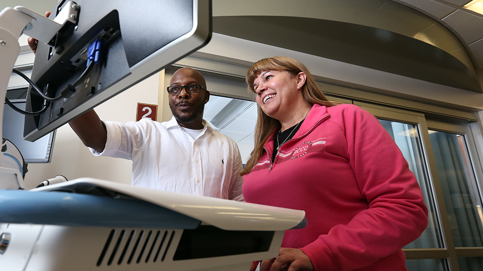 Student and instructor looking at a computer screen in a medical room
