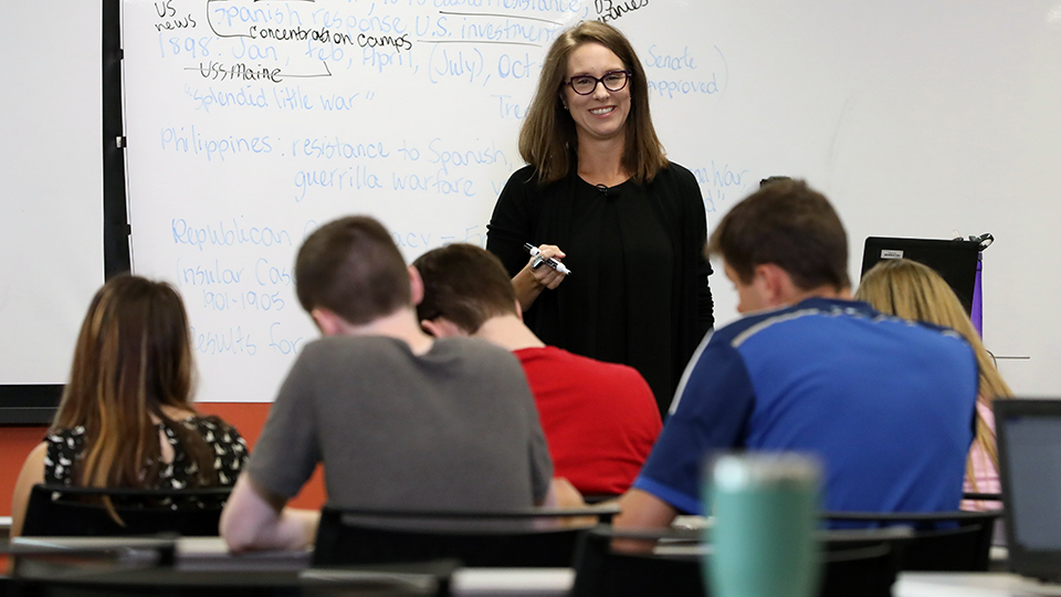 A teacher stands in front of a class of students.