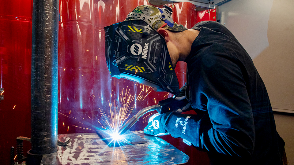 two jccc students looking at a piece of sheet metal in the welding lab