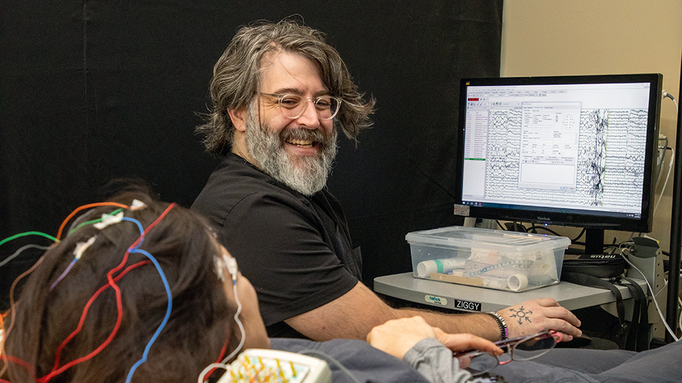 a man working with a patient and a computer program to practice Neurodiagnostic Technology techniques