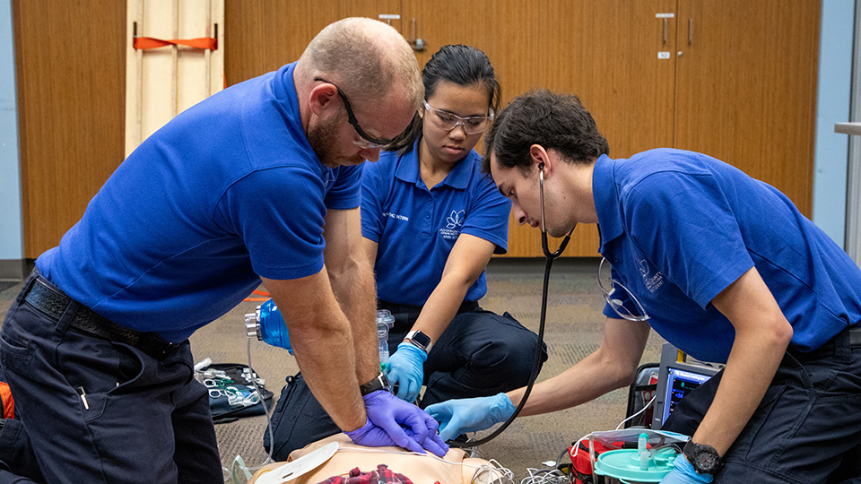Students practice CPR on a training device.