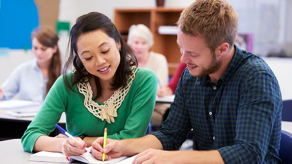 Two students examine a paper together.