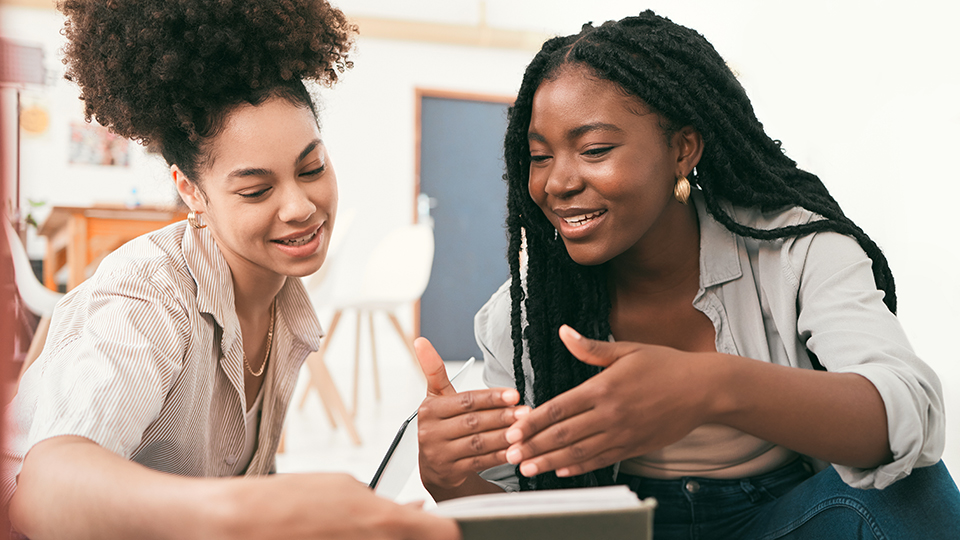 Two students look at a book together.