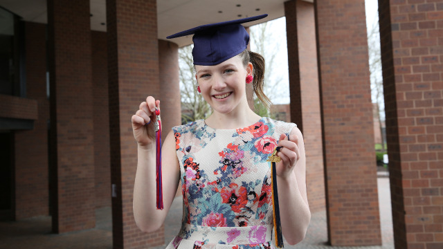Early College student holds both high school and college tassels.