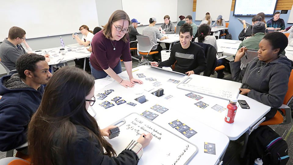  A teacher helps a group of students understand a chemistry assignment.