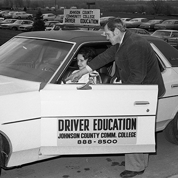 A driver's ed teacher shows a student the inside of a car.