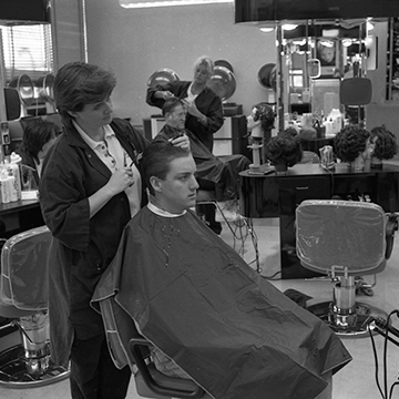 A cosmetology student cuts a man's hair.
