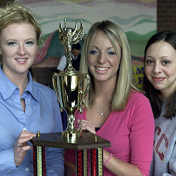 Three female students pose with a trophy.