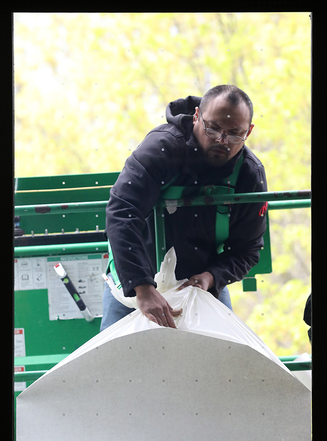 a worker installs vinyl dots to the outside of a window on the JCCC campus