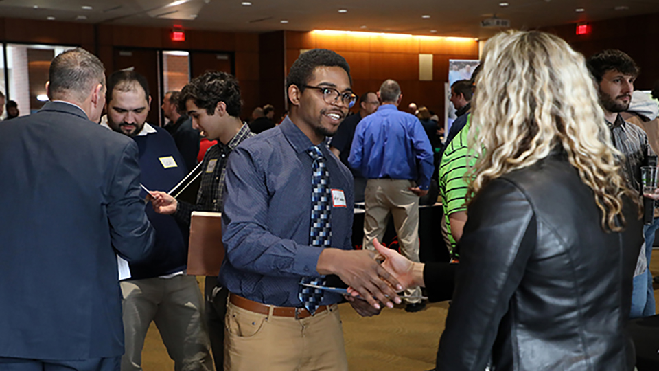 Student shaking hands with a business recruiter at a career fair