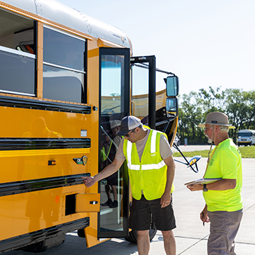  two cdl students inspect a school bus