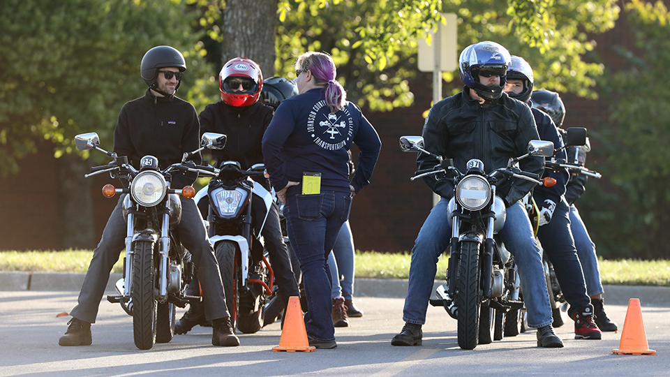 Four people on motorcycles line up for a training exercise