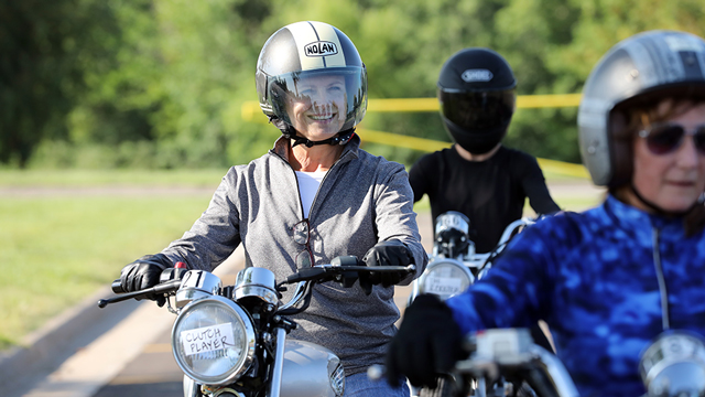 Three motorcycle students practicing driving skills. One is smiling and two are out of focus.
