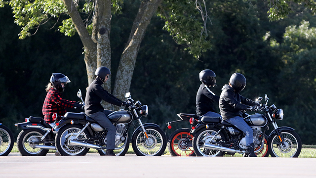 A group of 4 motorcycle students riding their bikes in the training lot