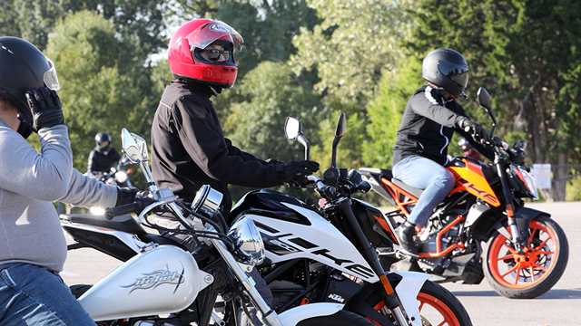 Three motorcycle students practice driving skills during class