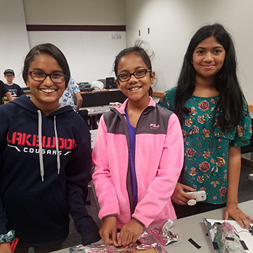 three female students stand smiling at the camera