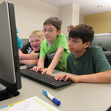 three young boys working at a computer