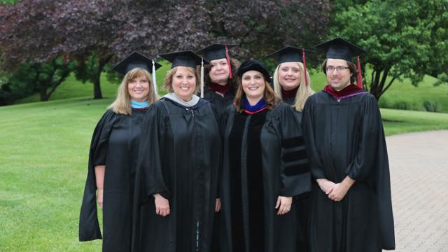 Full-time communications studies faculty group photo wearing graduation caps and gowns