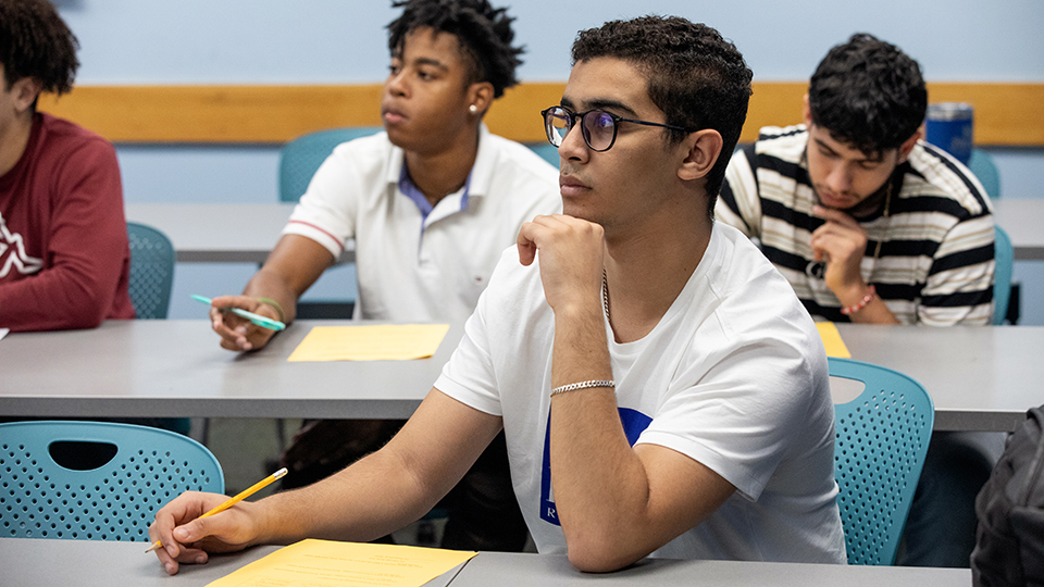 Students at classroom tables listening to a lecture