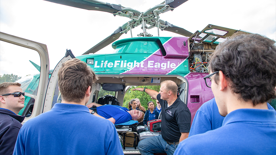 a group of JCCC EMS students practice loading a patient into a life flight helicopter