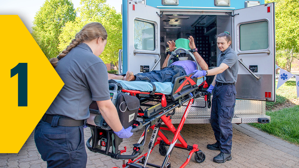 paramedic students practice loading a patient into the back of an ambulance