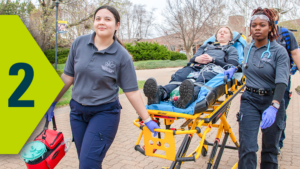 EMT students practice moving a volunteer patient on a stretcher