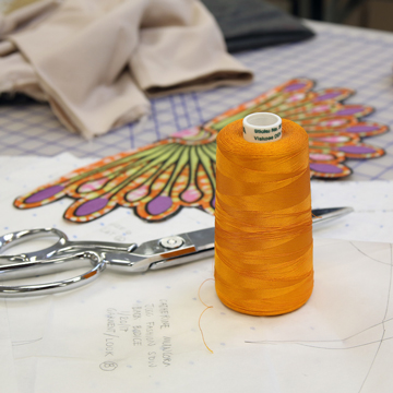 Thread and a pair of scissors on a worktable in the fashion design classroom