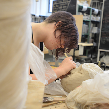 Student working on a ceramic head in the ceramics studio