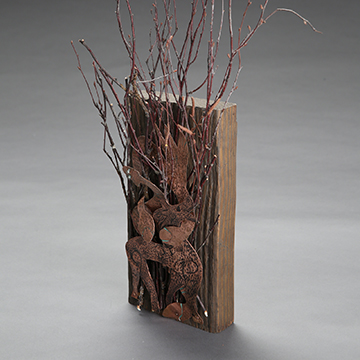 Metal sculpture of grass mounted on a block of wood