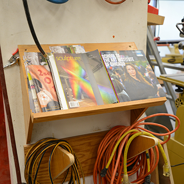 Sculpture magazines on a rack next to a drill press
