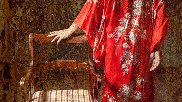 Model in a red kimono standing next to a chair