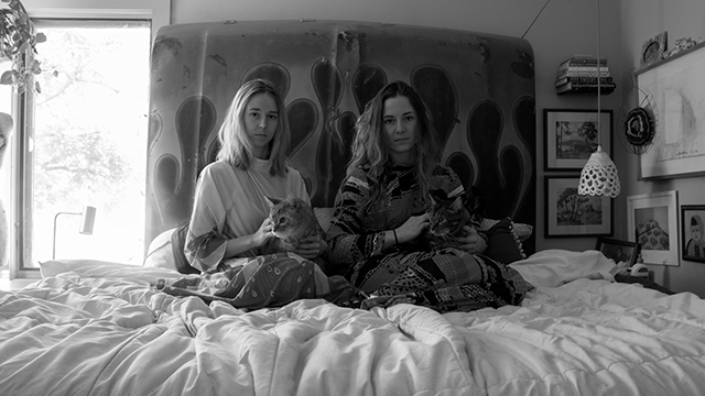 Black and white image of two girls sitting on a bed