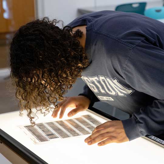 Student looking at negatives on a light table in the analog photography studio